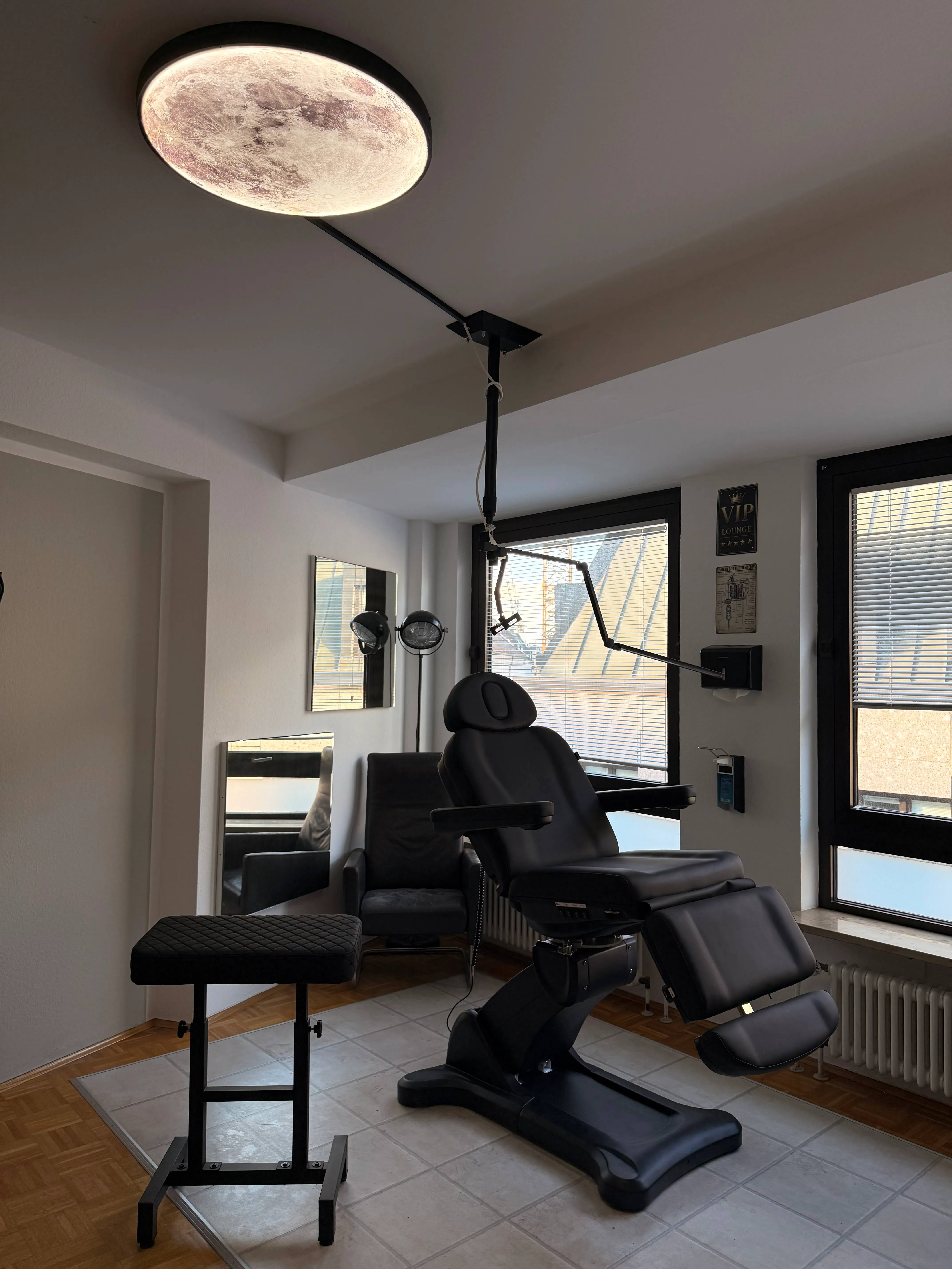 VIP-Behandlungsraum mit Tattoo-Liege und Fensterblick über die Dächer Münchens
